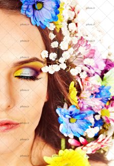 عکس نیمی از صورت زن با آرایش و مو های قهوه ای با تزئین گل های رنگی