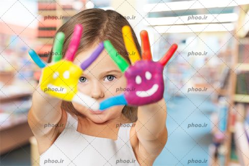 عکس دختر بچه در حال نمایش دادن دست های نقاشی شده