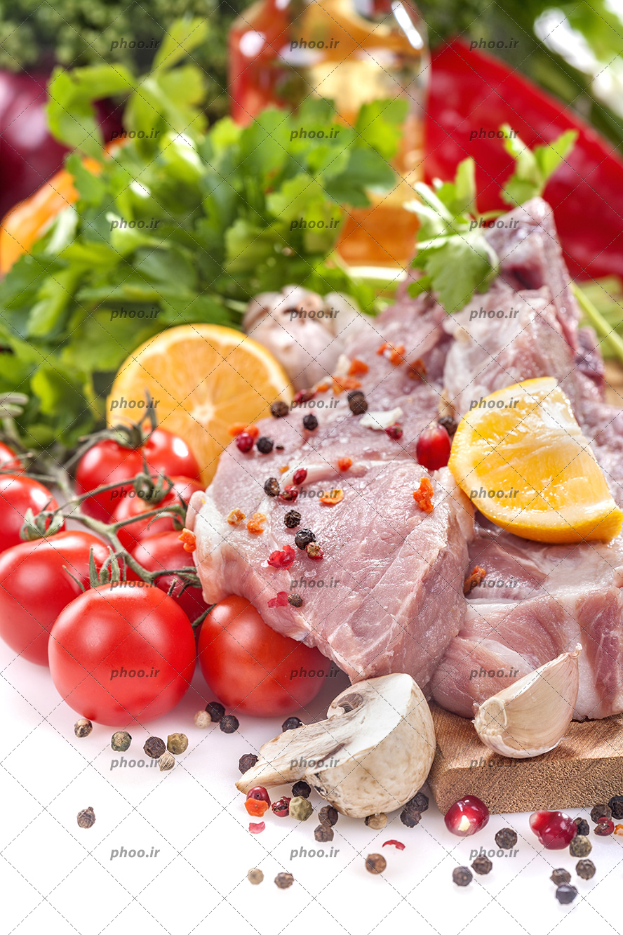 عکس گوشت خام در کنار ادویه و سبزیجات تازه در پس زمینه سفید
