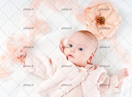 عکس با کیفیت نوزاد دختر زیبا با چشم های آبی و یک گل بالای سرش