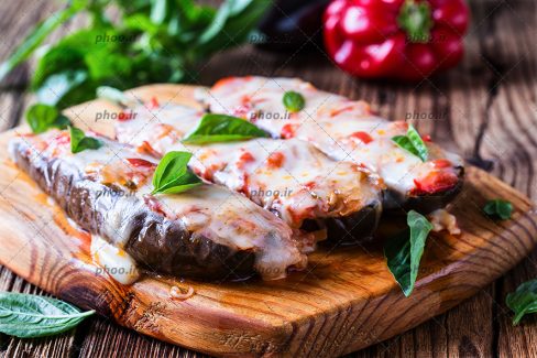 عکس بادمجان های شکم پر و تزئین سبزی روی تخته چوبی
