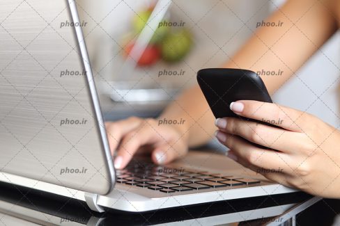 عکس دست های خانم در حال کار با گوشی و لپ تاپ