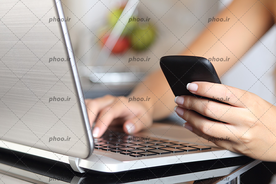 عکس دست های خانم در حال کار با گوشی و لپ تاپ