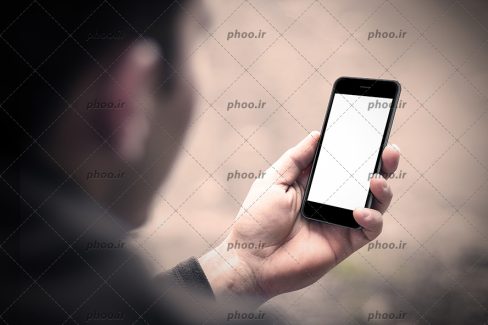 عکس گوشی در دست با صفحه سفید در پس زمینه محو