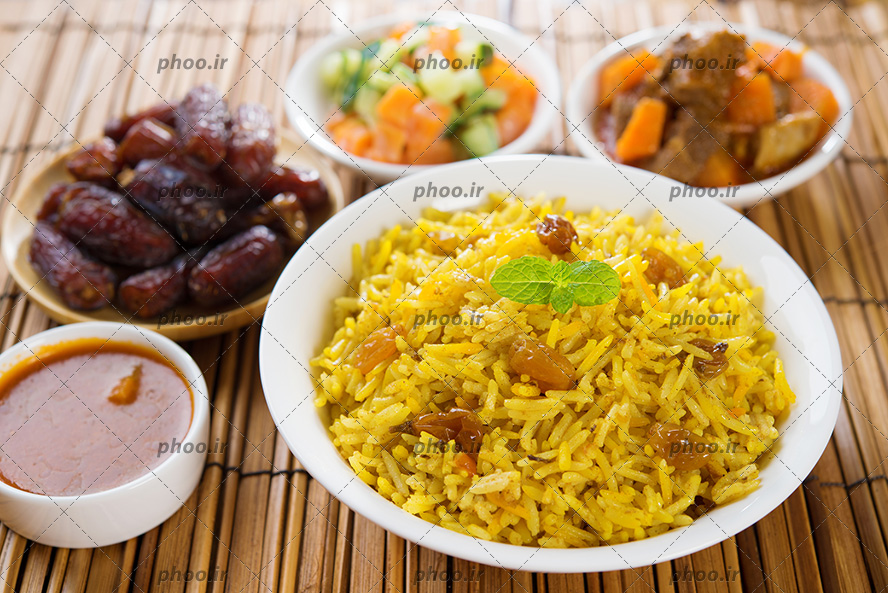 عکس غذای برنجی با خورشت و مخلفات کنار آن