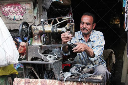 عکس مرد درحال کار با چرخ خیاطی