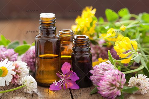 عکس زیبا عصاره گل در بطری شیشه ای روی میز باگل