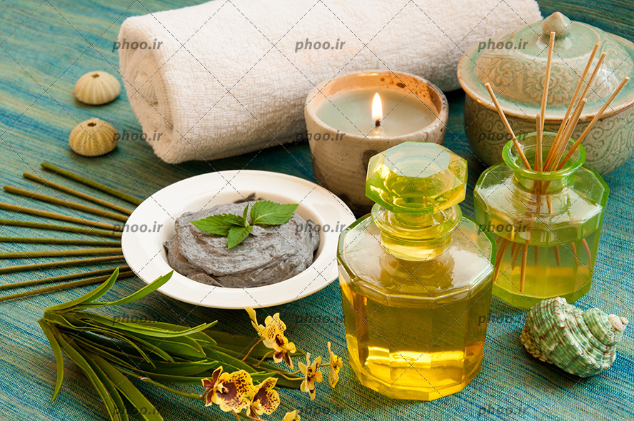 عکس زیبا بطری شیشه ای روغن ماساژ با شمع و سنگ و حوله