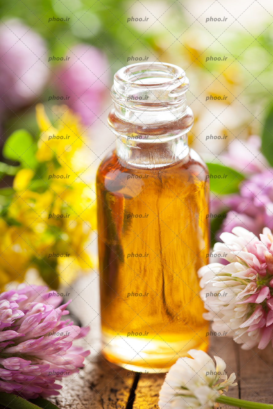 عکس زیبا عصاره گل در بطری شیشه ای روی میز باگل