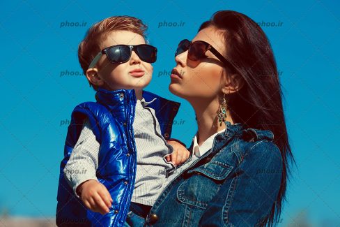 عکس با کیفیت مادر و پسر زیبا با عینک آفتابی در پس زمینه آبی