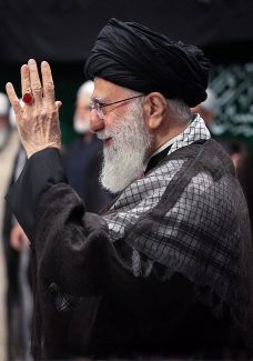 عکس با کیفیت مقام معظم رهبری ایستاده در جمعی از مردم و در حال سلام دادن با دست خود در حالت نیم رخ