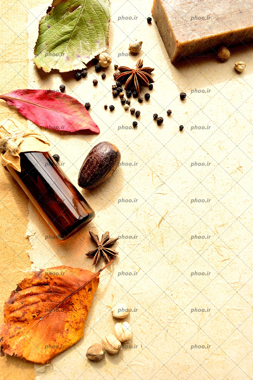 عکس شیشه روغن و دانه ها و صابون در پس زمینه کاغذی