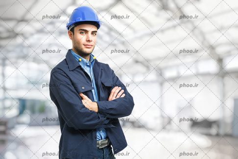 عکس مهندس جوان با لبخند و کلاه ایمنی در پس زمینه ساختمان در حال ساخت