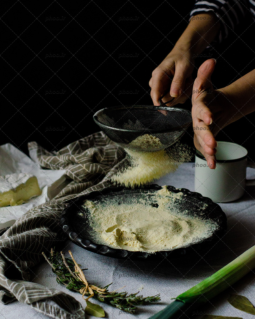 عکس الک کردن آرد در ظرف مشکی و تم مشکی