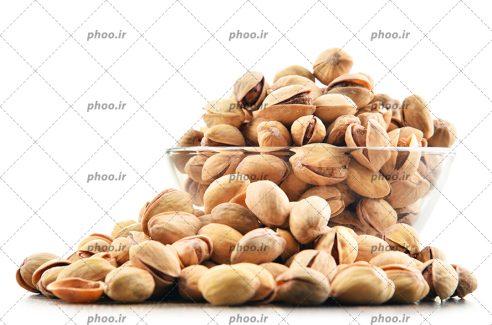 عکس پسته هایی روی زمین و داخل کاسه در پس زمینه سفید