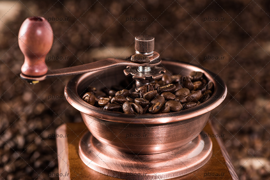عکس آسیاب قهوه و دانه های قهوه در آن از نمای نزدیک