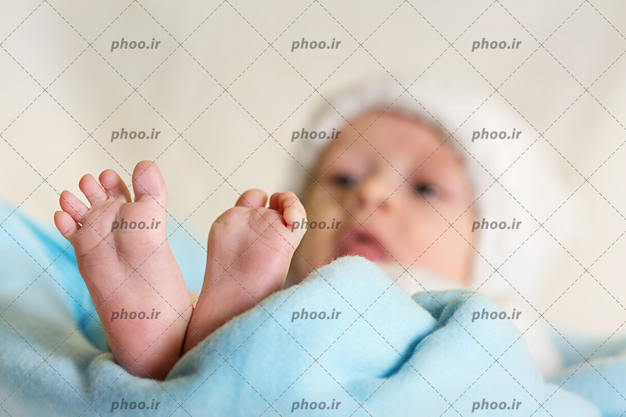 عکس با کیفیت نوزاد تازه متولد شده با کلاه روی پتوی آبی