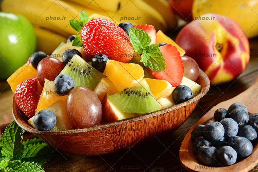 عکس کاسه چوبی از برش های میوه تازه و رنگی