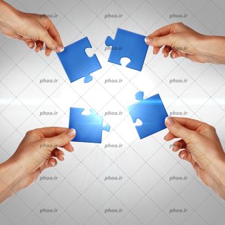 عکس با کیفیت دست ها در حال قرار دادن تکه های پازل آبی در کنار هم