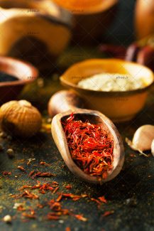 عکس زعفران در قاشق چوبی و روی زمین در پس زمینه مشکی