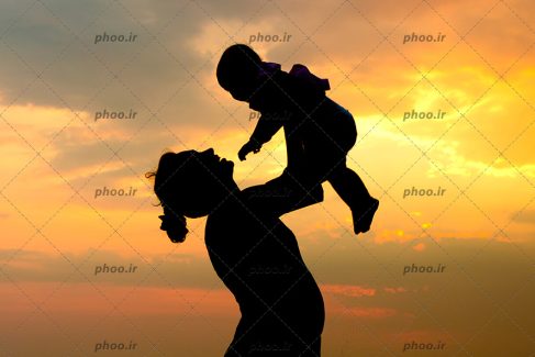 عکس با کیفیت مادر مهربان در حال بازی با کودک در برابر غروب خورشید