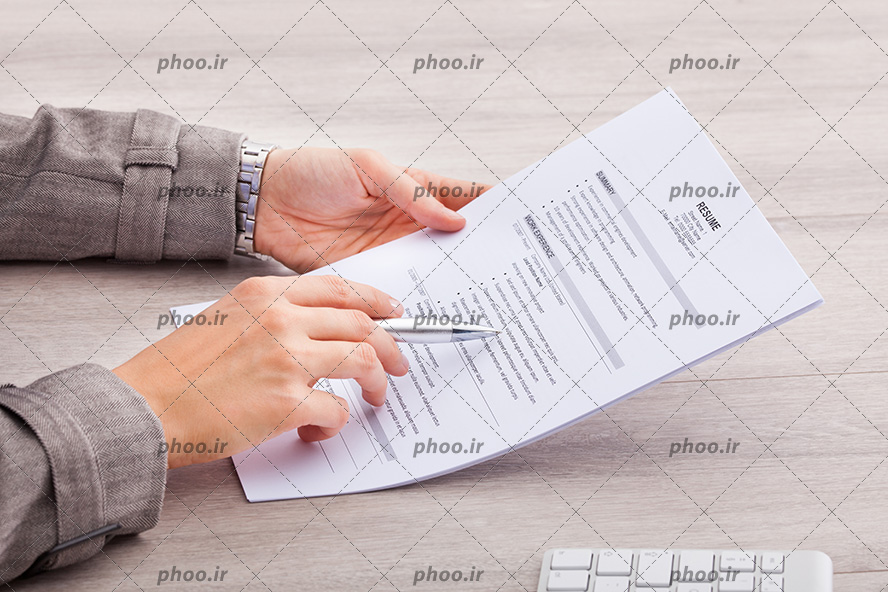 عکس یک آقا در حال مطالعه برگه و یک خودکار در دست