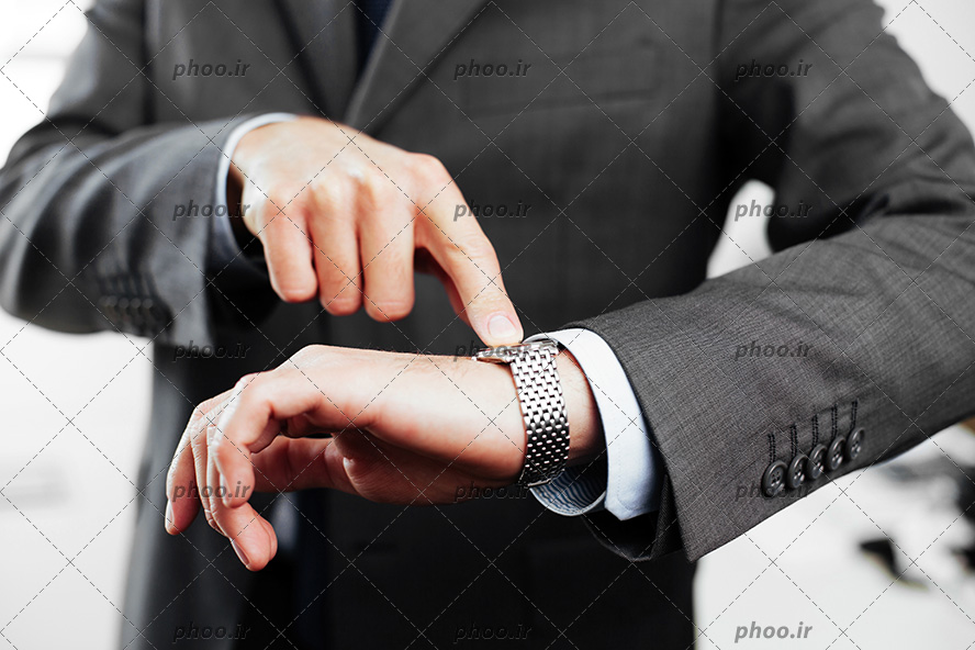 عکس مرد ایستاده و در حال اشاره کردن به ساعت