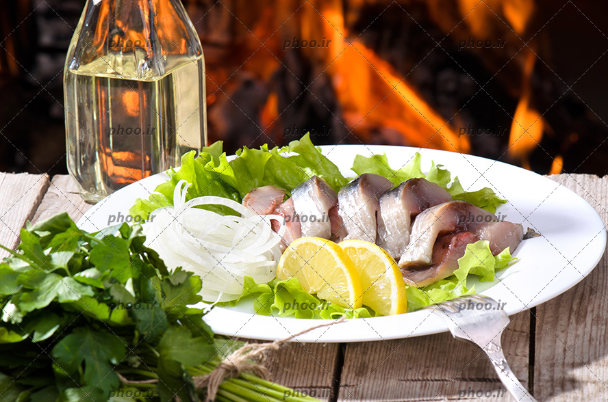 عکی ماهی در کنار لیمو و پیار و سبزی داخل دیس