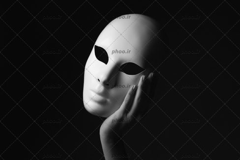 عکس ماسک در دست در پس زمین مشکی