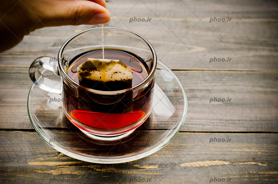 عکس فنجان چای با یک چای کیسه ای داخل آن از نمای بالا
