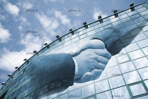 عکس با کیفیت و تبلیغاتی دست دادن دو تاجر بر روی یک ساختمان بزرگ در برابر آسمان ابری