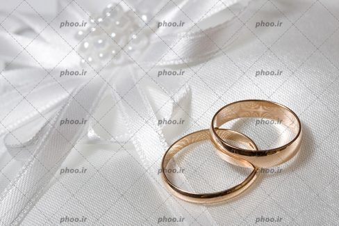 عکس با کیفیت حلقه های طلایی ازدواج روی پارچه سفید