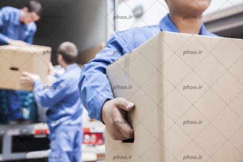عکس با کیفیت کارگران در حال تخلیه بسته های کارتن از داخل ماشین