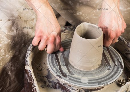 عکس با کیفیت سفالگر در حال جدا کردن سفال گلی از روی چرخ سفالگری