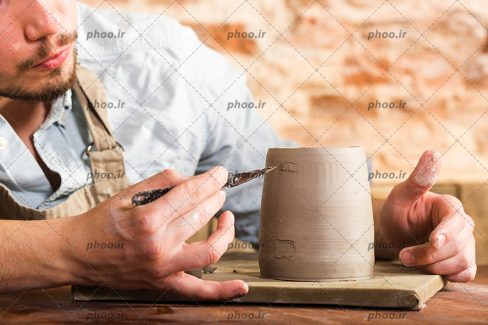 عکس با کیفیت سفالگر در حال علامت زدن روی گِل از نمای نزدیک