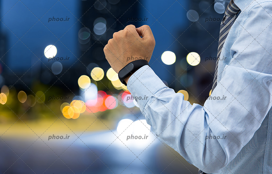 عکس دستبند الکترونیکی در دست مرد در پس زمینه نور های رنگی