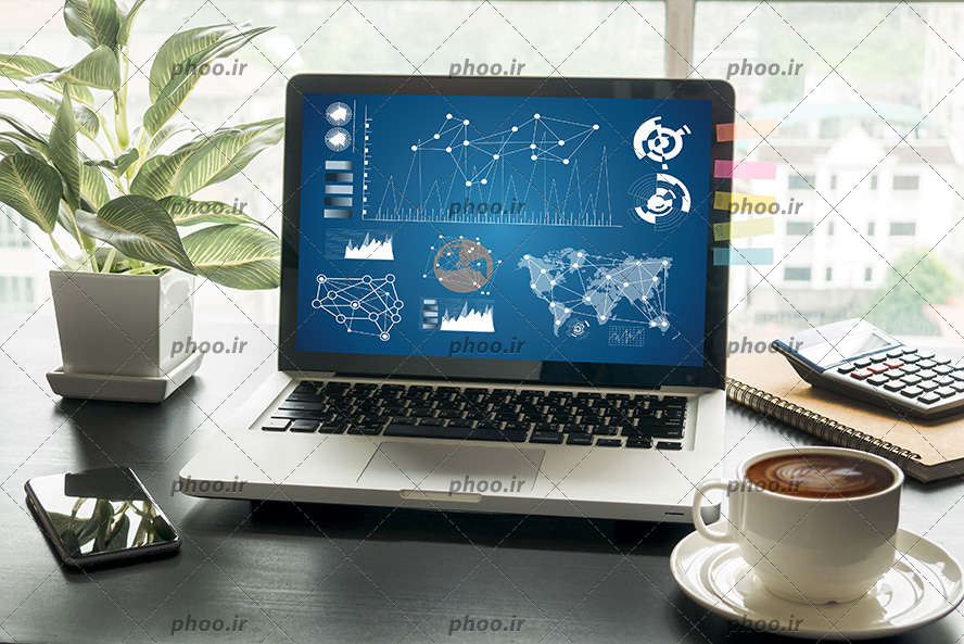 عکس لپ تاپ با نمودار های رسانه ای روی صفحه آن در کنار گوشی هوشمن و فنجان قهوه و گلدان روی میز