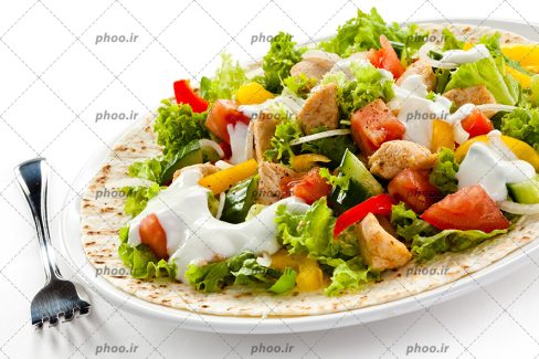 عکس با کیفیت سالاد سزار حاوی سبزیجات و مرغ روی نان در بشقابی سفید