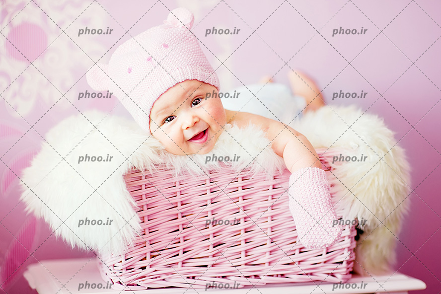 عکس با کیفیت نوزاد زیبا با کلاه و دستکش بافتنی در سبد صورتی
