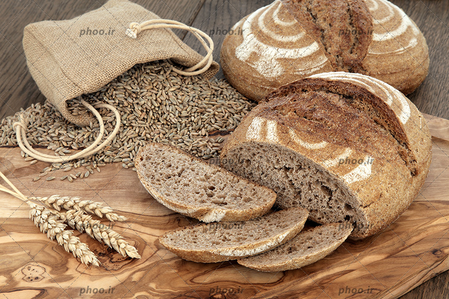 عکس نان چاودار و کیسه ی چاودار ریخته شده در پس زمینه چوبی