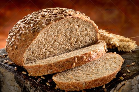 عکس نان گندم پخته شده صنعتی و خوشه گندم در پس زمینه قهوه ای