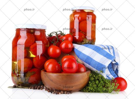 عکس گوجه فرنگی های تازه در کاسه چوبی و شیشه های ترشی گوجه فرنگی