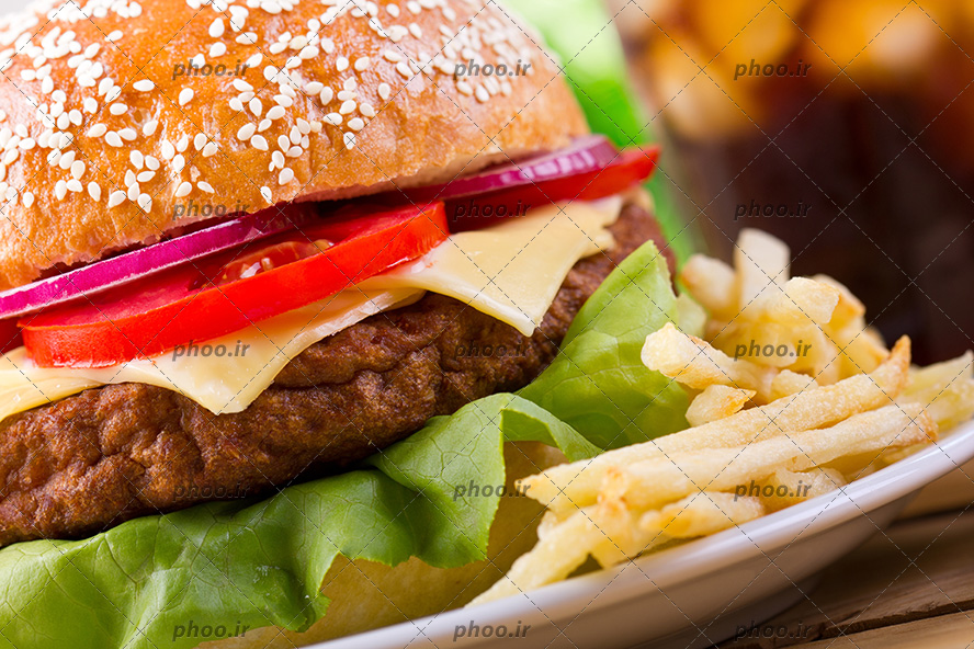 عکس ساندویچ چیز برگر با سبزیجات در کنار خلال سیب زمینی های سرخ شده