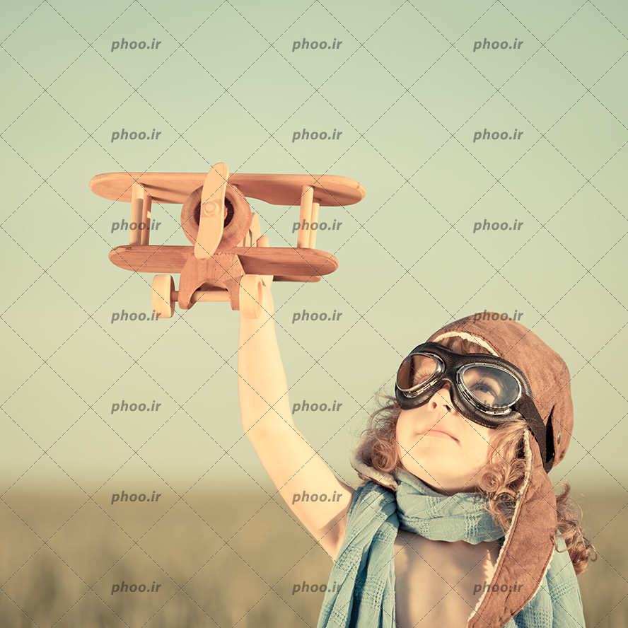 عکس با کیفیت بچه شاد در حال بازی با هواپیمای چوبی در پاییز
