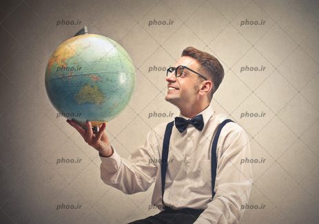 عکس با کیفیت مرد جوان با لبخند در حال نگاه کردن به کره زمین