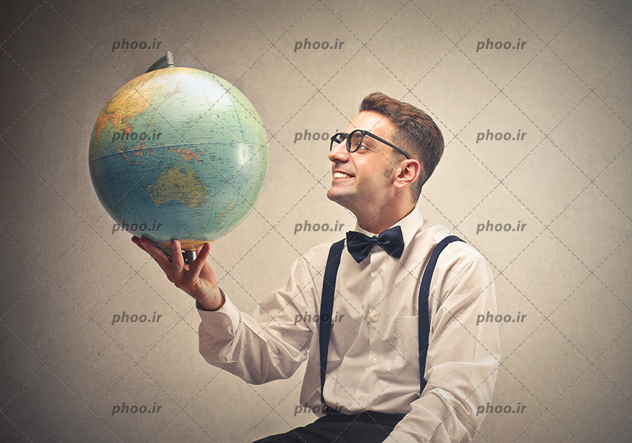 عکس با کیفیت مرد جوان با لبخند در حال نگاه کردن به کره زمین