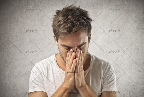عکس با کیفیت یک مرد ناامید که دست هایش را روی صورتش گرفته است