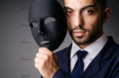 عکس با کیفیت مردی با ماسک سیاه در ست در پس زمینه خاکستری