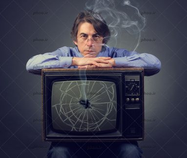 عکس با کیفیت مرد غمگین با یک تلویزیون شکسته روی پا در پس زمینه تیره