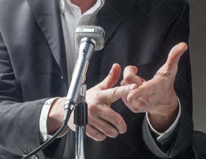 عکس دستان مرد و میکروفون درحال سخرانی
